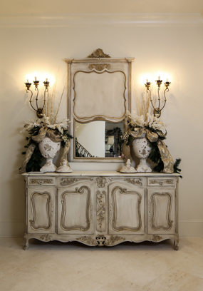 The walnut buffet in the entryway was originally in the dining room; Dee had it and the Trumeau mirror above it painted by local artist Frances Walker to be more in keeping with the rest of the home’s serene palette. The sconces are from Fireside Antiques. 