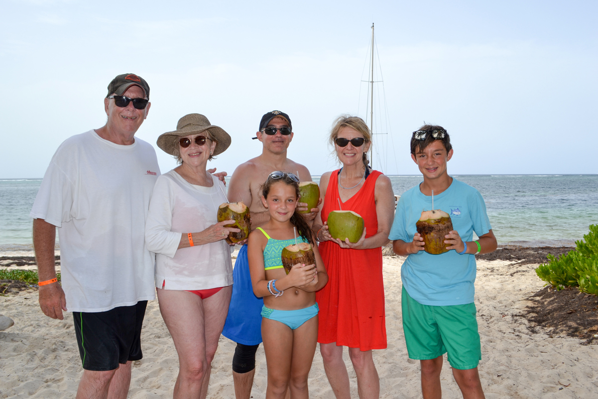 Bob, Beth, Tommy, Virginia, Julia and Andrew sip from coconuts near their chartered sailboat.