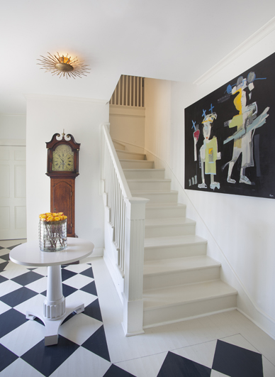 Artist Sally Conklin painted the black and white design on the foyer’s hardwood floor. A vibrant Tony Mose painting hangs along the stair wall. “I wanted visitors to get a sense of what was to unfold in the rest of the house, so the foyer—which is quite small—was a small gesture,” says Larkins.