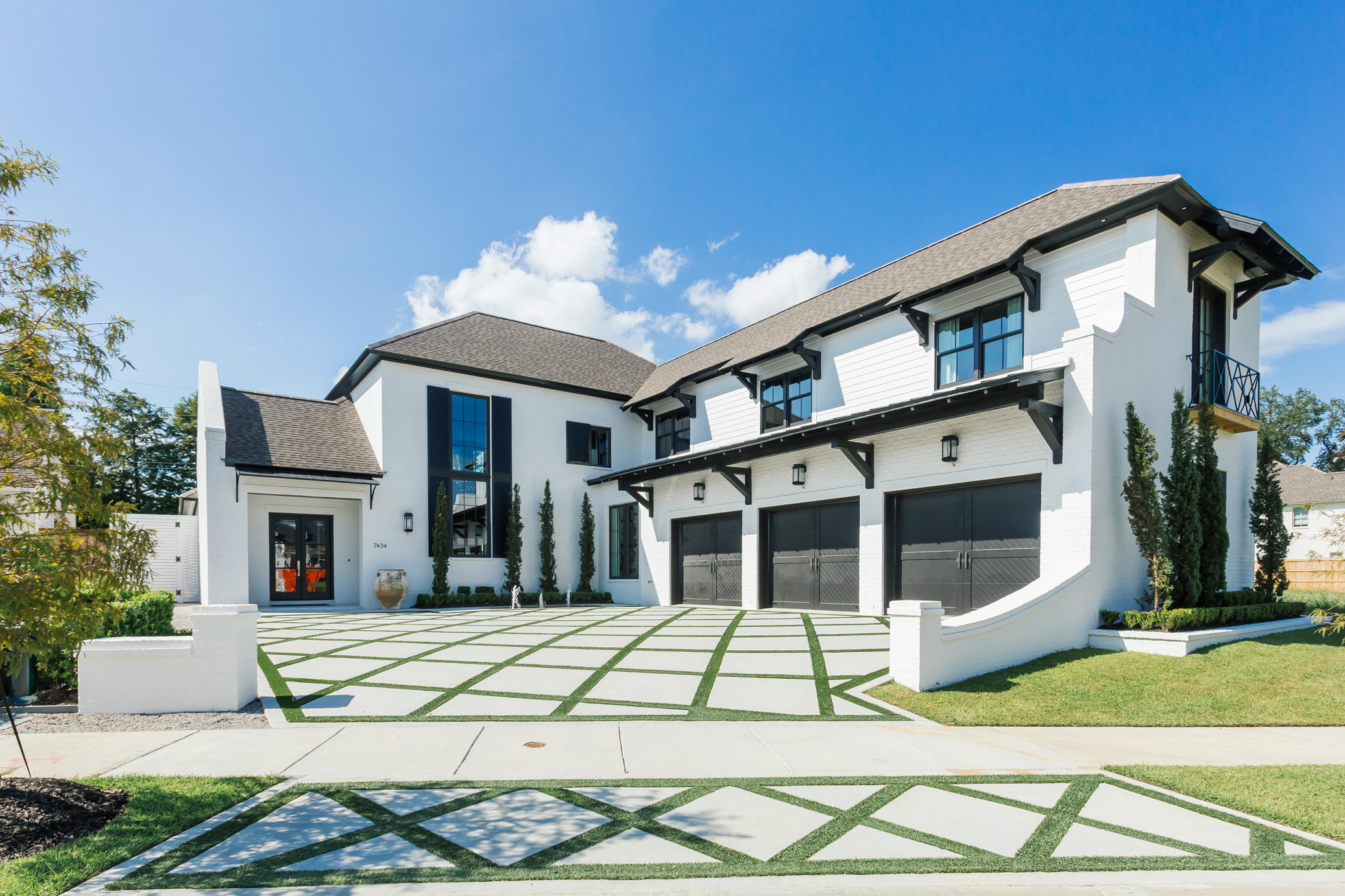 Bright white exterior paint contrasts with black trim for a bold modern statement that makes Jason’s home stand out in its location in the Settlement at Willow Grove. The driveway design was created by Turf-Logic using integrated artificial grass. 