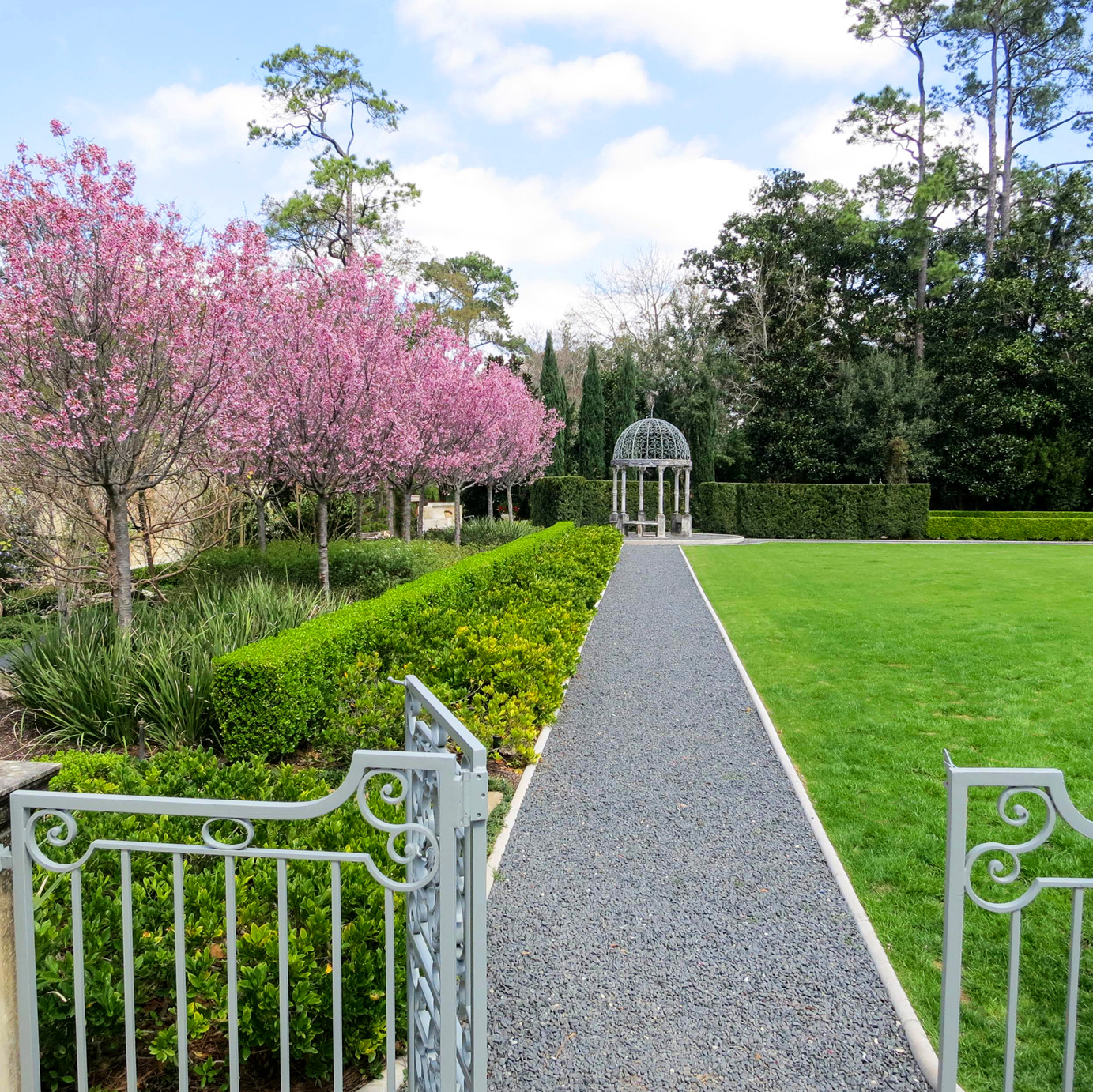 A gravel path lined by blooming cherry trees leads to an original Istrian marble pavilion at the Neal House.
