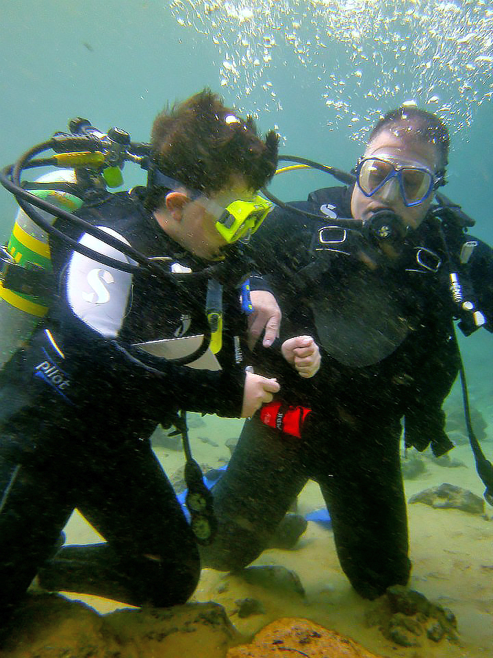 David Howard helps son Hunter on a recent diving trip.