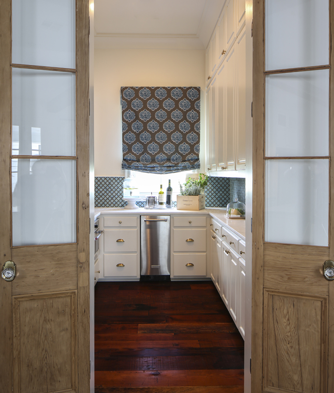 Antique cypress doors from New Orleans lead to the butler’s pantry, which features a bold blue tiled backsplash and white rhino marble countertops. 