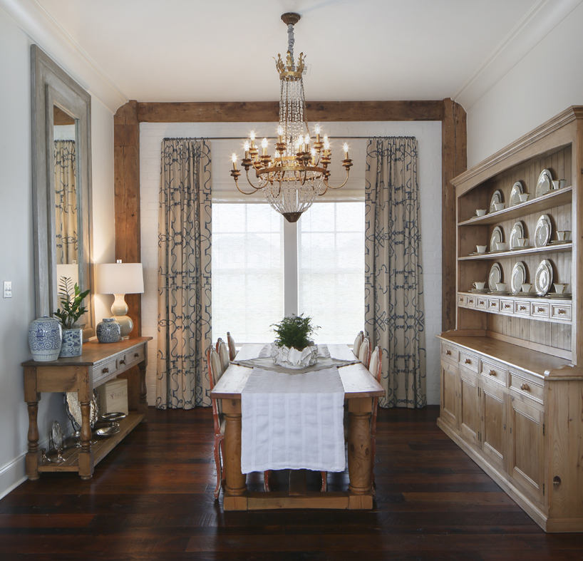A leftover antique pine beam was used to frame the window wall in the dining room. Textured and patterned drapes pick up the blue cues from the adjacent butler’s pantry.