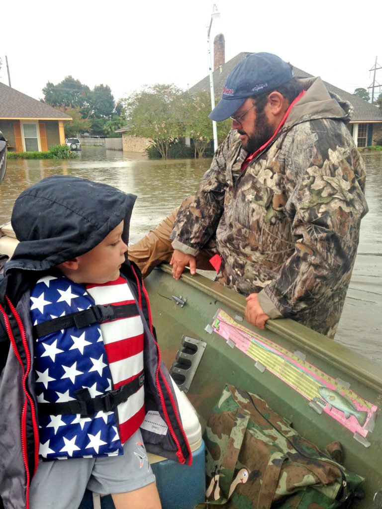 After a day spent rescuing residents in other parts of the city from rapidly rising waters, Chris Macaluso found himself using his boat to take his own family and neighbors to safety on August 14. Here, he climbed into the boat where his son Hank, who turned 4 just a few days after the flooding, was waiting with Macaluso’s wife Katie and 10-month-old daughter Maggie (not pictured). Photo courtesy Chris Macaluso.