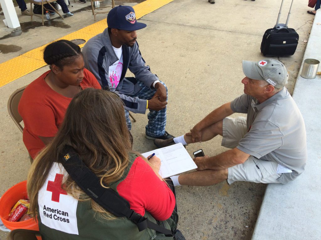 Tamika Chatman and Phillip Poydras, who lost everything in the floods, talk about their experiences with volunteers Virginia Hart and Craig Cooper outside the Red Cross shelter in Sorrento. Photo by: Patrick Pannett