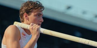 Pole vaulter Mondo Duplantis holds a pole on his shoulder and prepares for competition