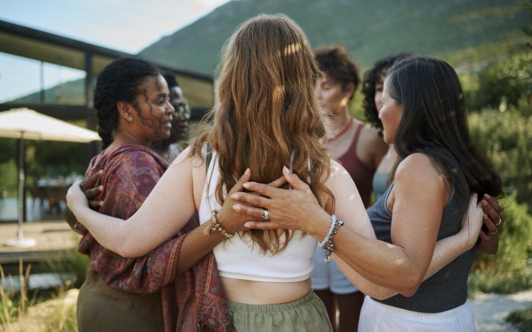 Diverse women standing arm in arm outdoors during a wellness retreat
