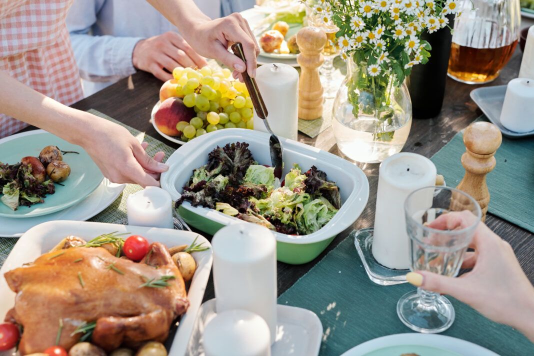 Hands of young female with spoon taking or mixing cooked vegetables on table